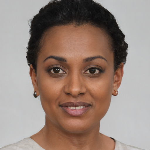 Joyful black young-adult female with short  black hair and brown eyes