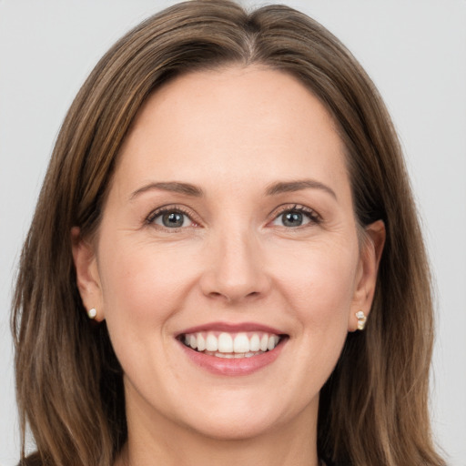 Joyful white adult female with long  brown hair and grey eyes