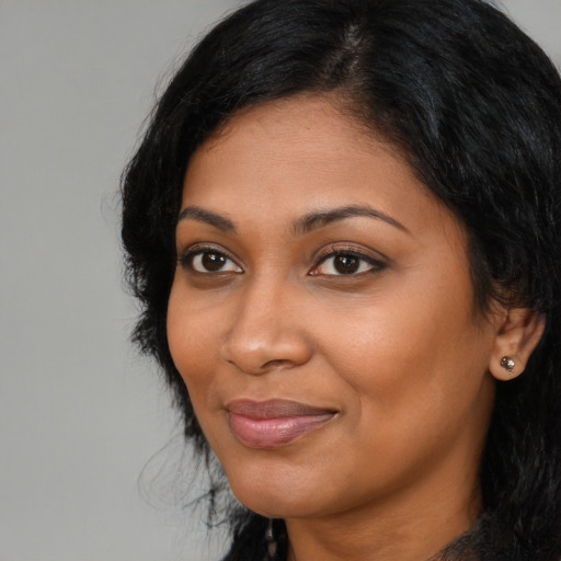 Joyful black young-adult female with long  black hair and brown eyes