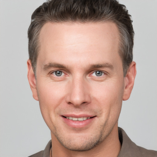 Joyful white young-adult male with short  brown hair and grey eyes