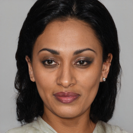 Joyful latino adult female with medium  black hair and brown eyes