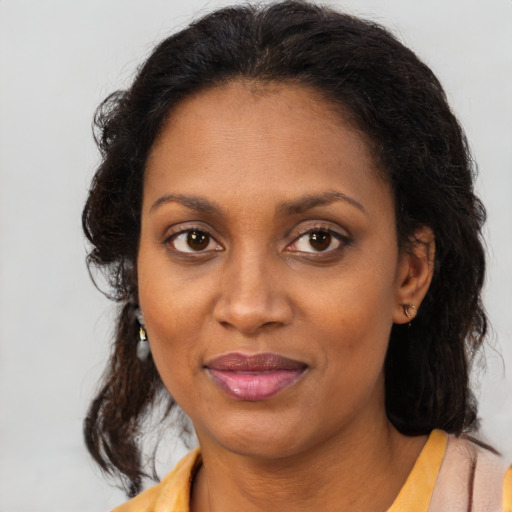 Joyful black young-adult female with long  brown hair and brown eyes