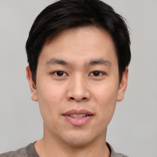 Joyful asian young-adult male with short  black hair and brown eyes