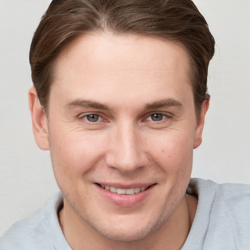 Joyful white young-adult male with short  brown hair and grey eyes