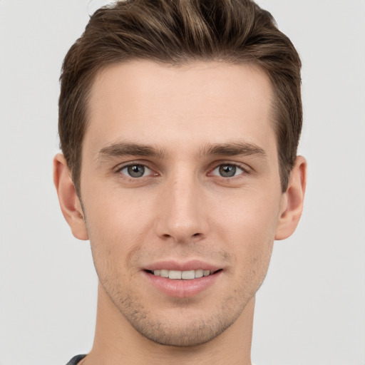 Joyful white young-adult male with short  brown hair and grey eyes