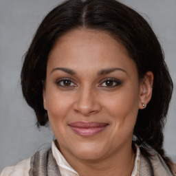 Joyful latino adult female with medium  brown hair and brown eyes