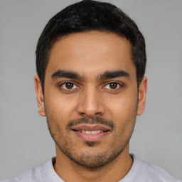 Joyful latino young-adult male with short  black hair and brown eyes