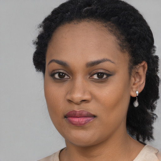 Joyful black young-adult female with long  black hair and brown eyes