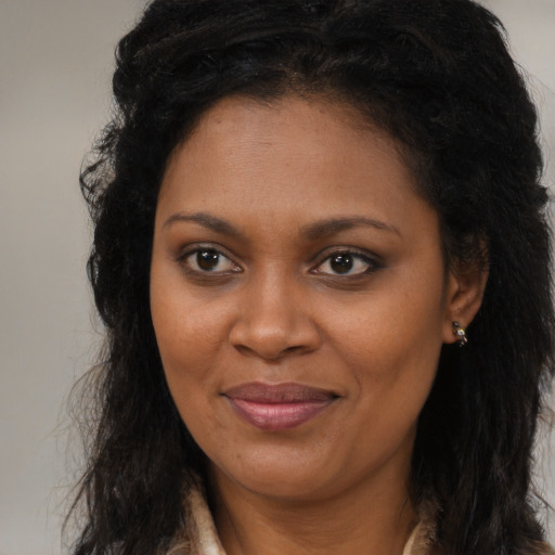 Joyful black young-adult female with long  brown hair and brown eyes