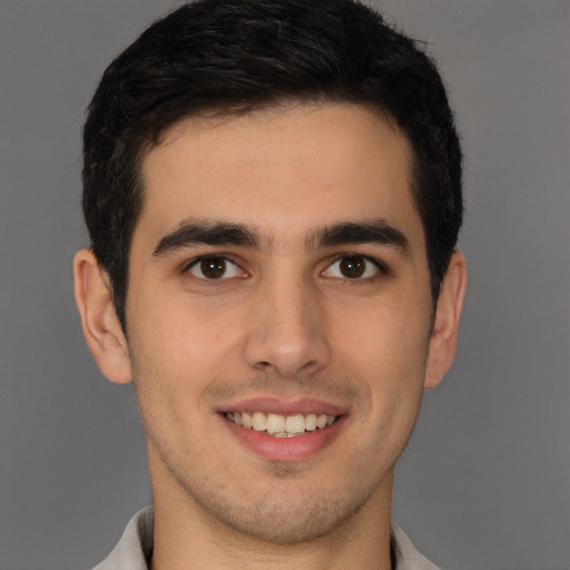 Joyful latino young-adult male with short  brown hair and brown eyes
