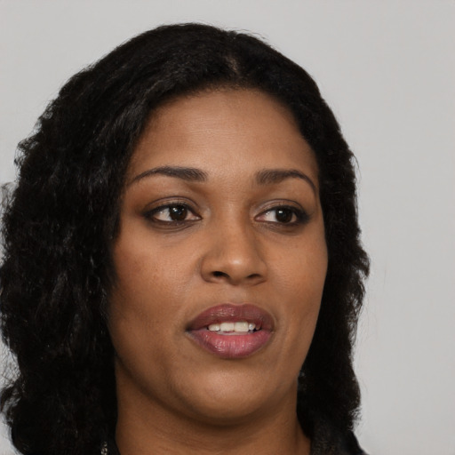 Joyful black young-adult female with long  brown hair and brown eyes
