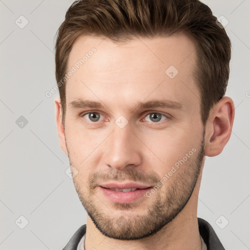 Joyful white young-adult male with short  brown hair and grey eyes