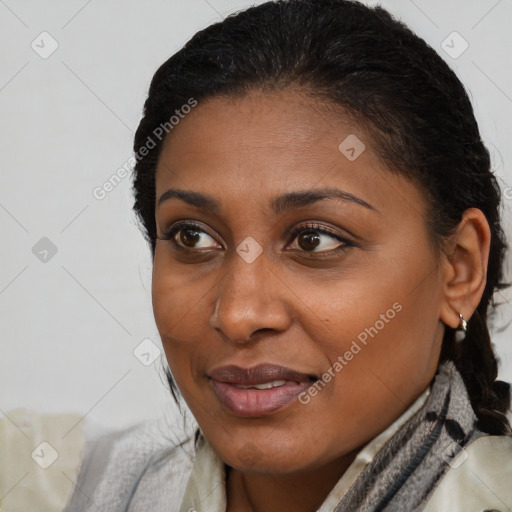 Joyful black young-adult female with long  brown hair and brown eyes