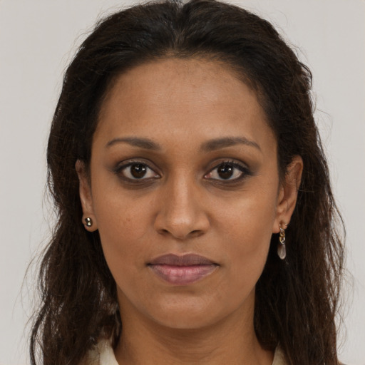 Joyful black young-adult female with long  brown hair and brown eyes