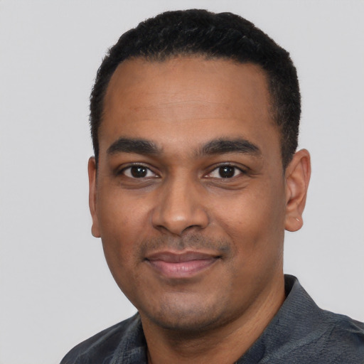 Joyful black young-adult male with short  black hair and brown eyes