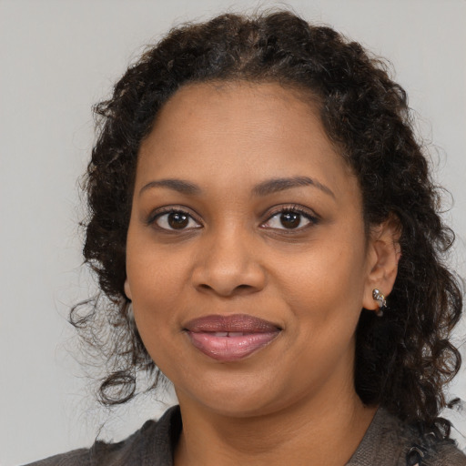 Joyful black young-adult female with long  brown hair and brown eyes