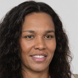 Joyful black adult female with long  brown hair and brown eyes