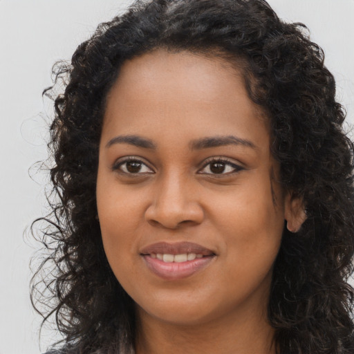 Joyful black young-adult female with long  brown hair and brown eyes