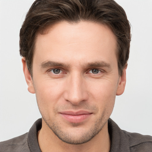 Joyful white young-adult male with short  brown hair and grey eyes