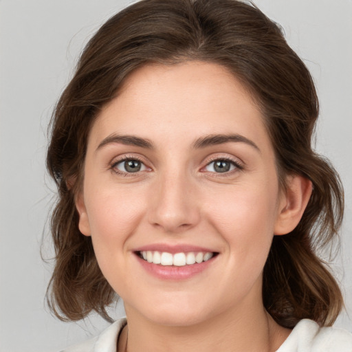 Joyful white young-adult female with medium  brown hair and grey eyes