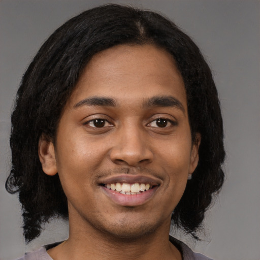 Joyful black young-adult male with medium  black hair and brown eyes