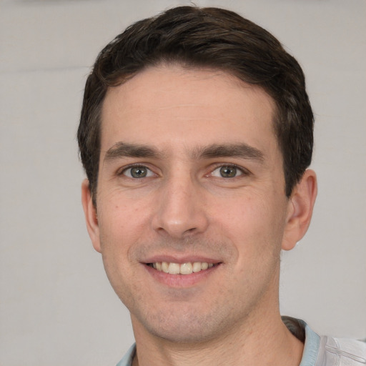 Joyful white young-adult male with short  brown hair and grey eyes