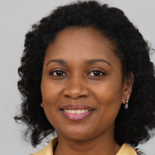 Joyful black young-adult female with long  brown hair and brown eyes