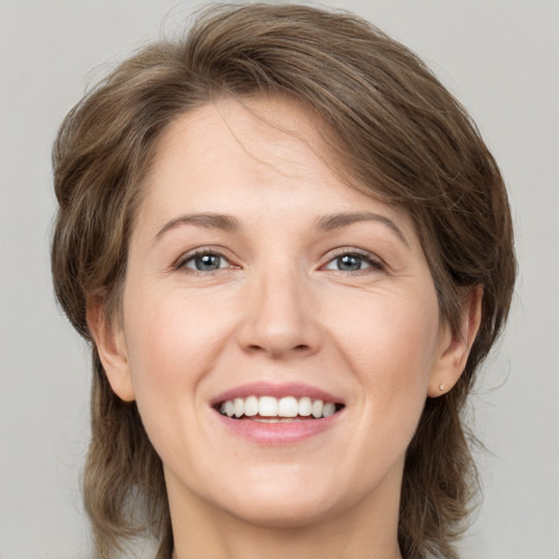 Joyful white young-adult female with medium  brown hair and grey eyes