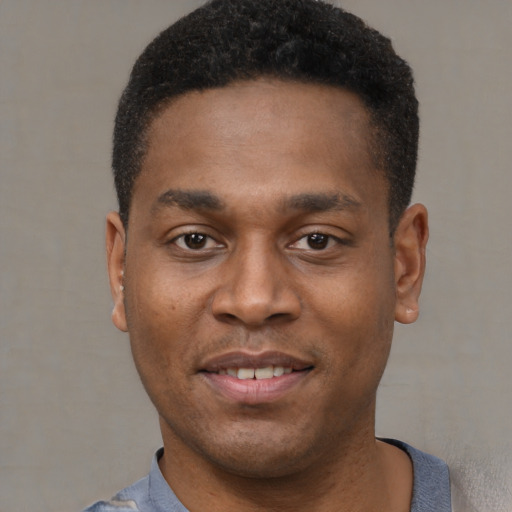 Joyful black young-adult male with short  black hair and brown eyes