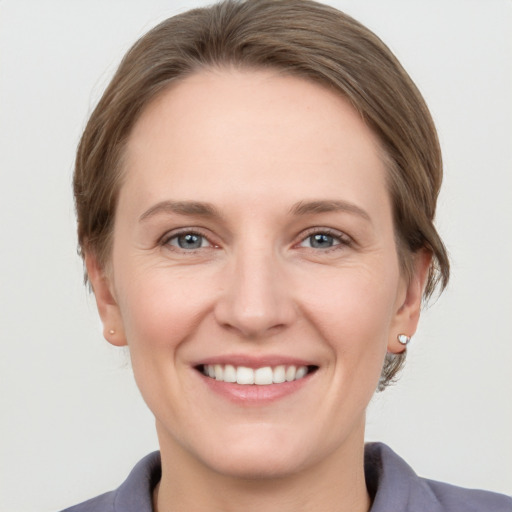 Joyful white young-adult female with medium  brown hair and grey eyes