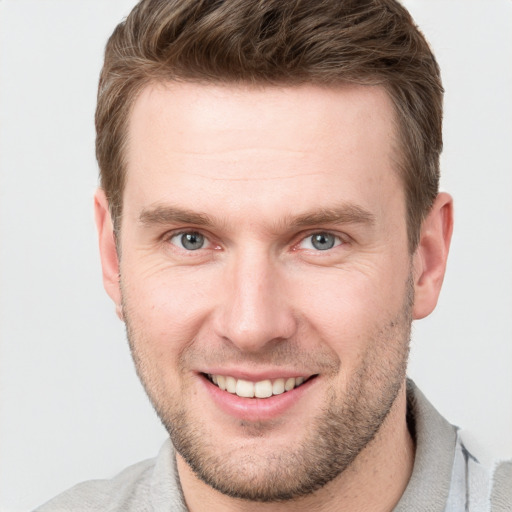 Joyful white young-adult male with short  brown hair and grey eyes