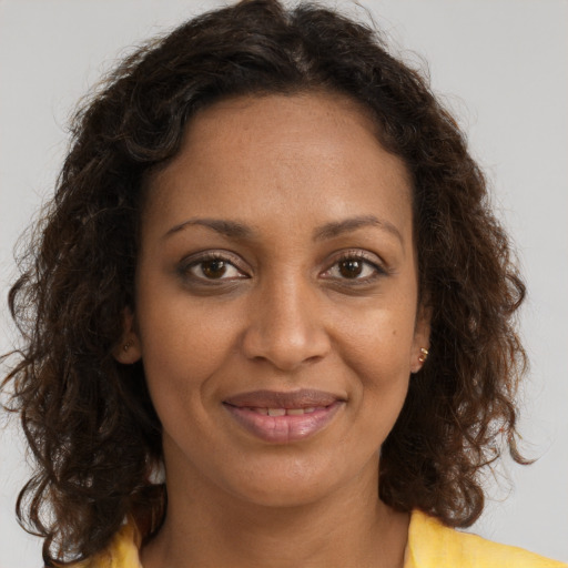 Joyful black adult female with long  brown hair and brown eyes