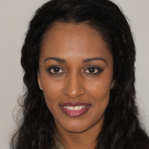 Joyful black young-adult female with long  brown hair and brown eyes