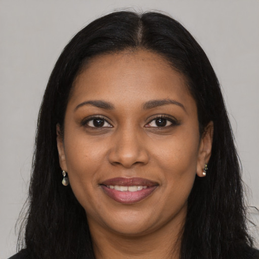 Joyful black young-adult female with long  brown hair and brown eyes