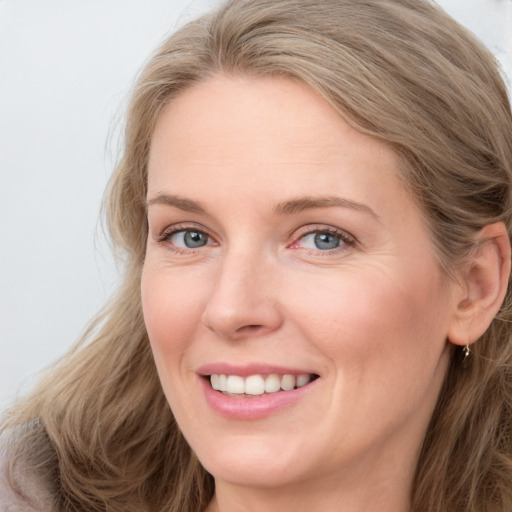 Joyful white adult female with long  brown hair and blue eyes