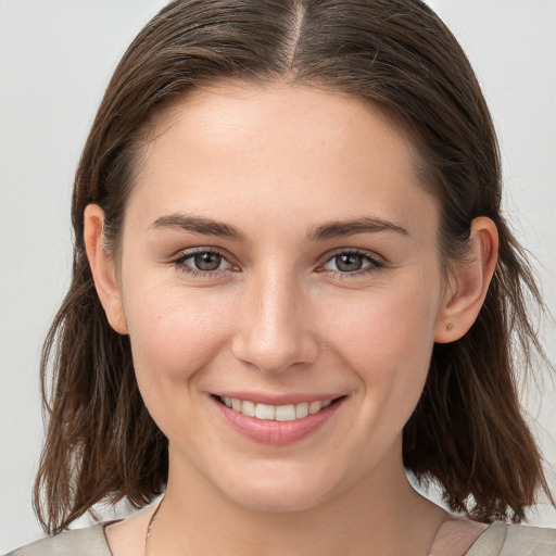 Joyful white young-adult female with medium  brown hair and grey eyes