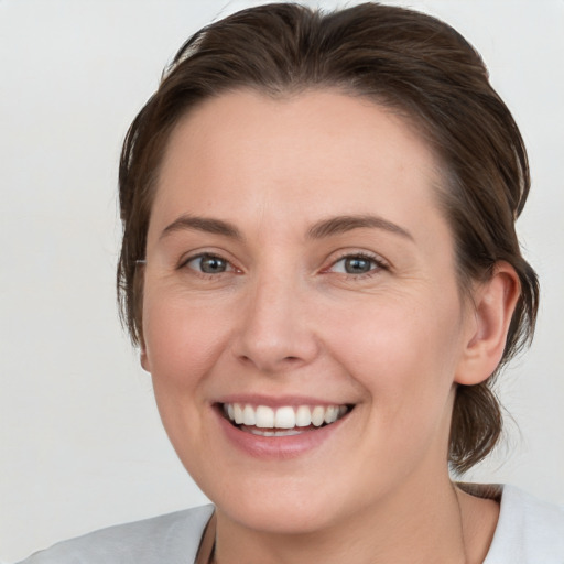 Joyful white young-adult female with medium  brown hair and grey eyes