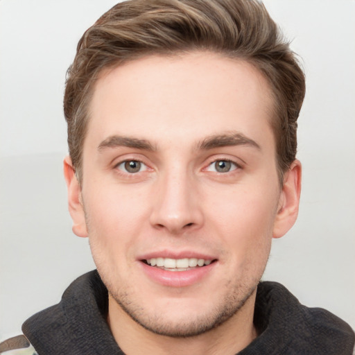 Joyful white young-adult male with short  brown hair and grey eyes