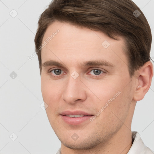 Joyful white young-adult male with short  brown hair and grey eyes