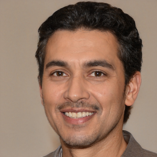 Joyful white adult male with short  black hair and brown eyes