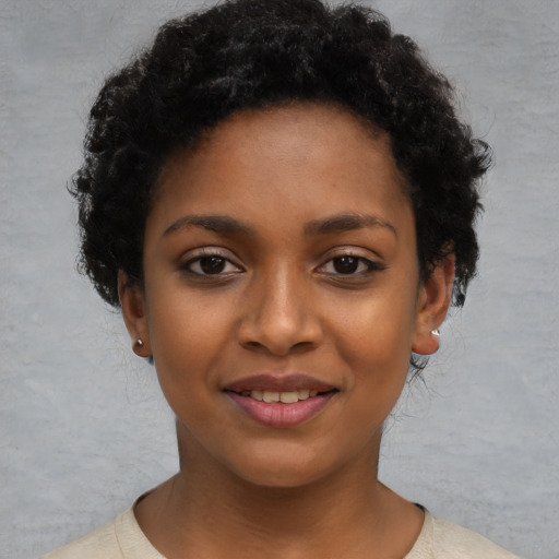 Joyful black young-adult female with short  black hair and brown eyes