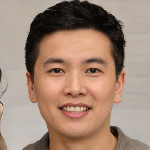 Joyful asian young-adult male with short  brown hair and brown eyes