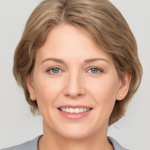 Joyful white adult female with medium  brown hair and grey eyes