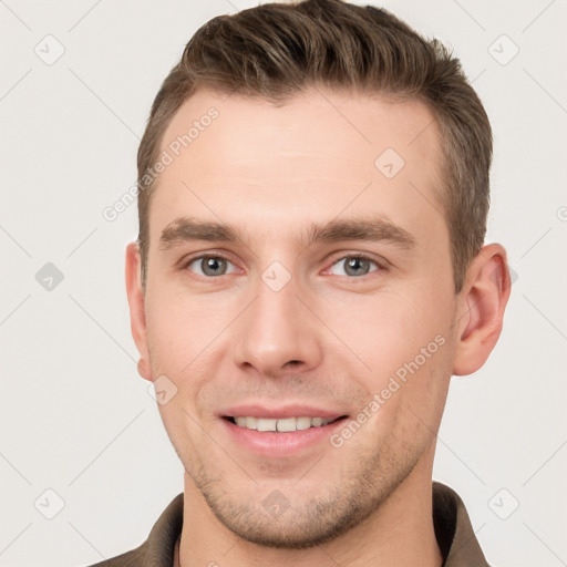 Joyful white young-adult male with short  brown hair and grey eyes