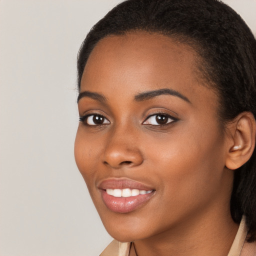 Joyful black young-adult female with long  brown hair and brown eyes