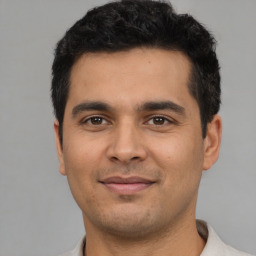 Joyful latino young-adult male with short  black hair and brown eyes