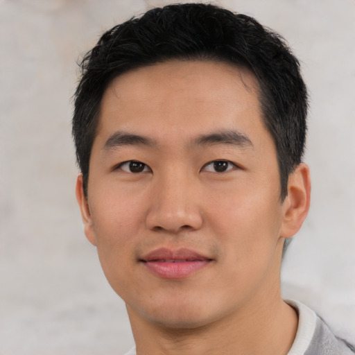 Joyful asian young-adult male with short  black hair and brown eyes