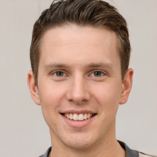 Joyful white young-adult male with short  brown hair and grey eyes