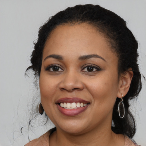 Joyful black young-adult female with long  black hair and brown eyes