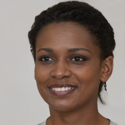 Joyful black young-adult female with short  black hair and brown eyes